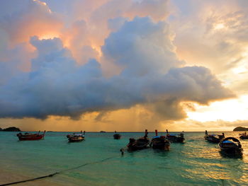 Boats moored in sea against sky during sunset