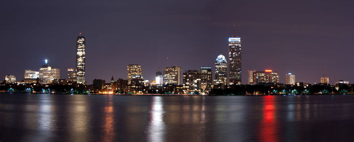 Illuminated city skyline by charles river against sky at night