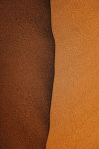 Full frame shot of sand at the top of a dune divided starkly between light and dark