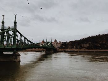 Bridge over river against cloudy sky