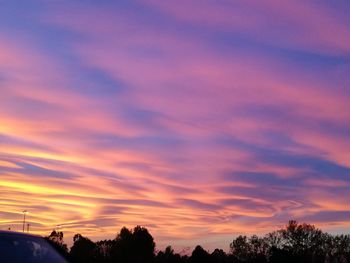 Silhouette trees against dramatic sky during sunset