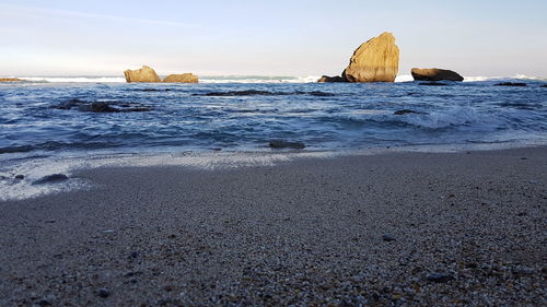 Rock formation on beach against sky