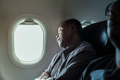 Mature man sleeping while sitting in airplane