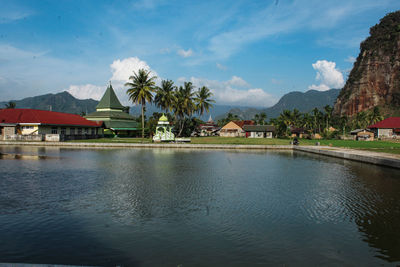 Houses by swimming pool by lake against sky