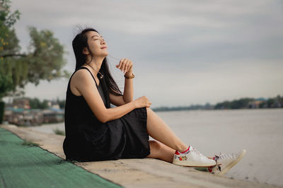 Side view of young woman sitting on table