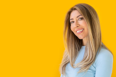 Portrait of young woman against yellow background