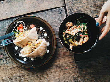 Cropped hand of woman with food on wooden table