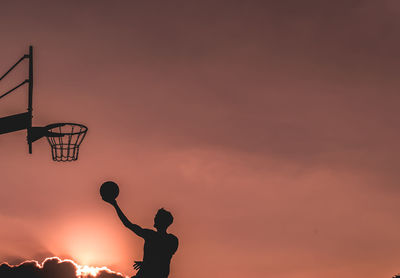 Low angle view of basketball hoop against sky during sunset