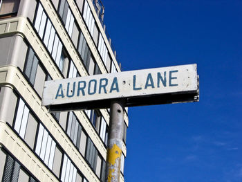 Low angle view of road sign against blue sky