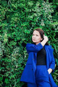 Beautiful woman standing against ivy covered wall