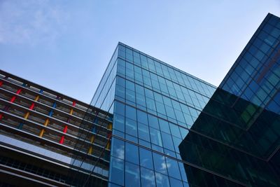 Low angle view of modern glass building against clear blue sky