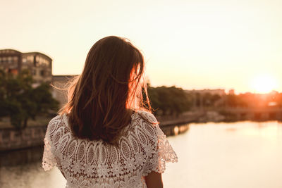 Rear view of woman standing against sky during sunset