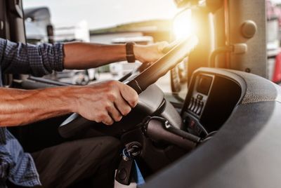 Midsection of man holding steering wheel in bus