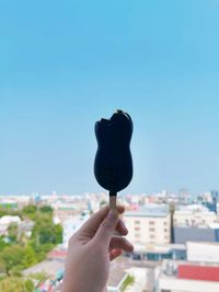 Midsection of person holding ice cream against clear sky