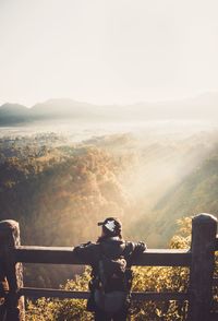 Man standing on railing by mountain against sky