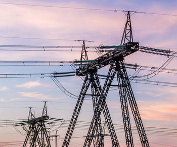 Low angle view of silhouette electricity pylon against sky during sunset