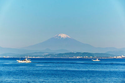 Scenic view of sea and snowcapped mountain against clear sky in the morning