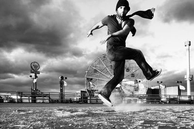 Low angle view of woman jumping against cloudy sky