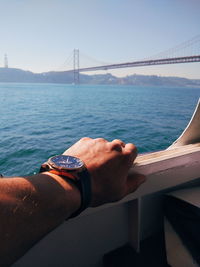 Man hand on bridge over sea against clear sky