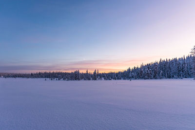 Scenic view of snow covered land against sky during sunset