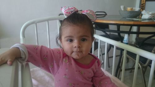 Portrait of cute girl sitting in crib at home