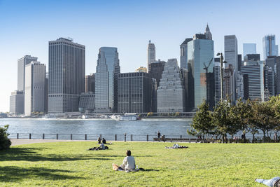 People in park by buildings against sky in city