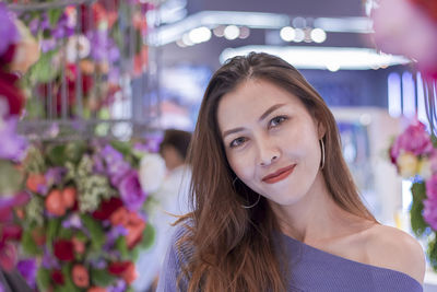 Portrait of smiling woman standing against bouquet