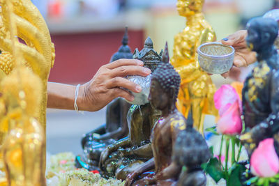 Cropped image of hand pouring water on buddha statue