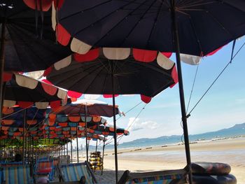 Umbrellas hanging on beach against sky