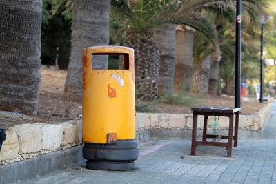 Close-up of yellow box on footpath against wall