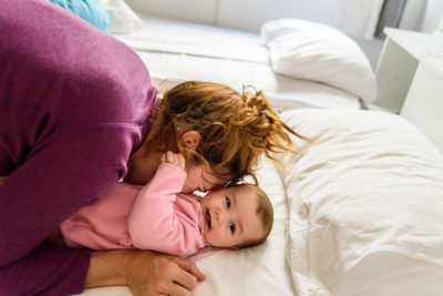 Mother and baby lying on bed at home