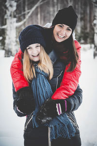 Portrait of smiling woman with daughter standing in snow