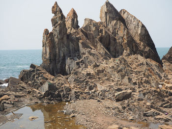 Rock formations on shore against clear sky