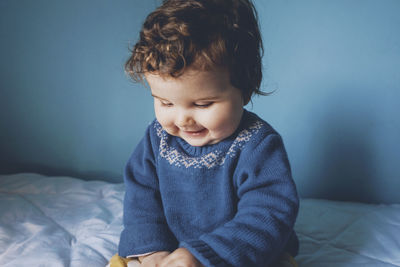 Cute girl sitting on bed at home