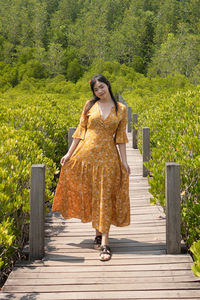 Woman walking on footpath amidst plants