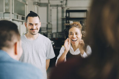 Happy businesswoman and businessman with colleagues in creative office