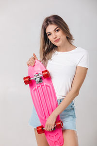 Portrait of smiling young woman holding gift against white background