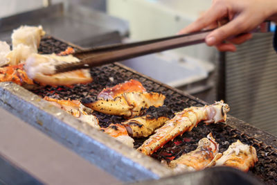 Hand holding meat on barbecue grill
