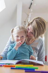 Happy mother and daughter sitting at home