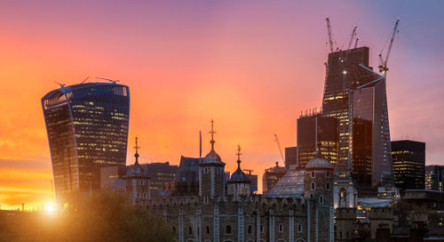 Modern buildings in city against sky during sunset