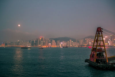 Illuminated ship sailing in sea against sky at dusk