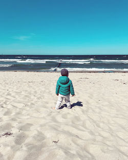 Rear view of man on beach against sky