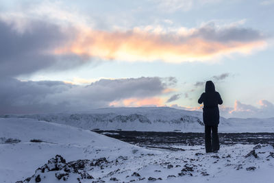 Rear view of person standing on snow covered land