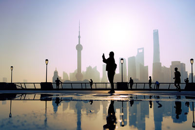 Silhouette people on water against clear sky