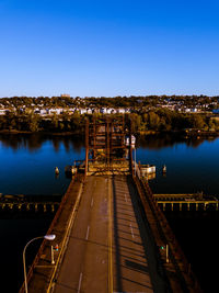 Illuminated pier over lake against clear blue sky at night