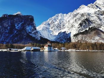 Scenic view of lake by snowcapped mountains against sky