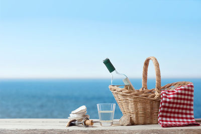 Wicker basket on table by sea against sky