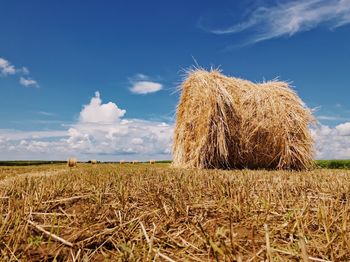 Hay bale on land against sky during summer