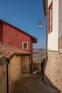 Narrow alley in an ancient village with vineyard hills in the background, monforte, cuneo, piemonte 