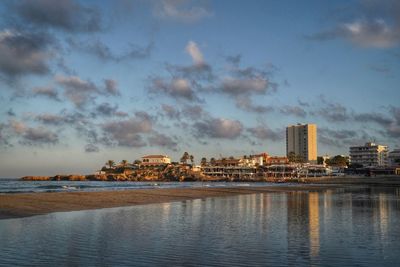 Sea by buildings against sky